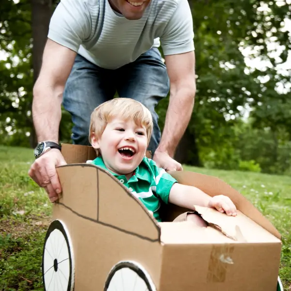 Little boy pushed cardboard car
