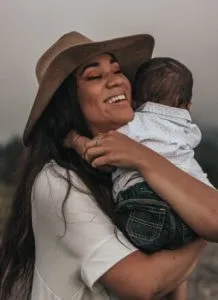 parent wearing brown hat holding a baby