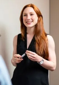 smiling woman black dress wearing watch holding pen
